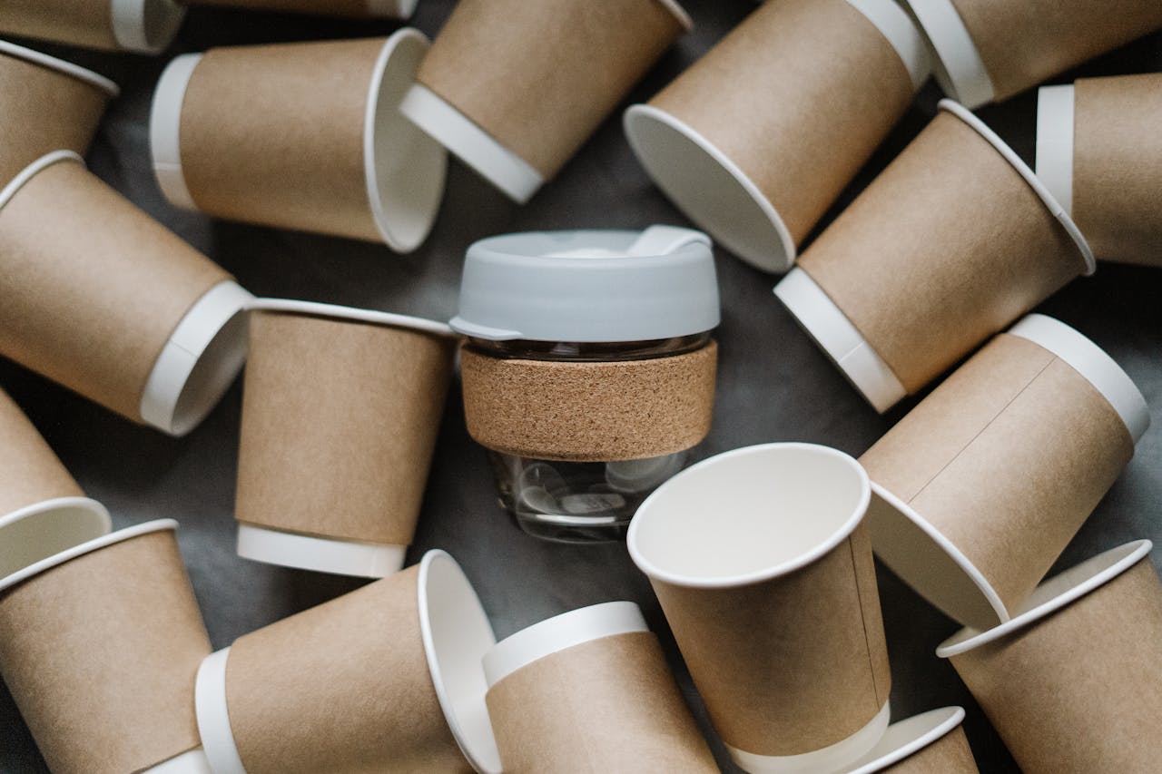 A reusable cup surrounded by disposable paper cups emphasizes zero waste and sustainability.